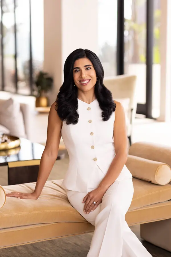 San Diego Realtor Shirin Kheshti sits on a golden sofa