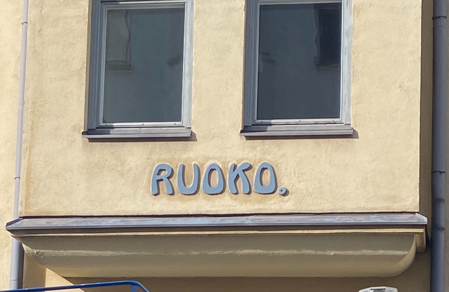 Playful art nouveau lettering mounted on a pale yellow building in Helsinki