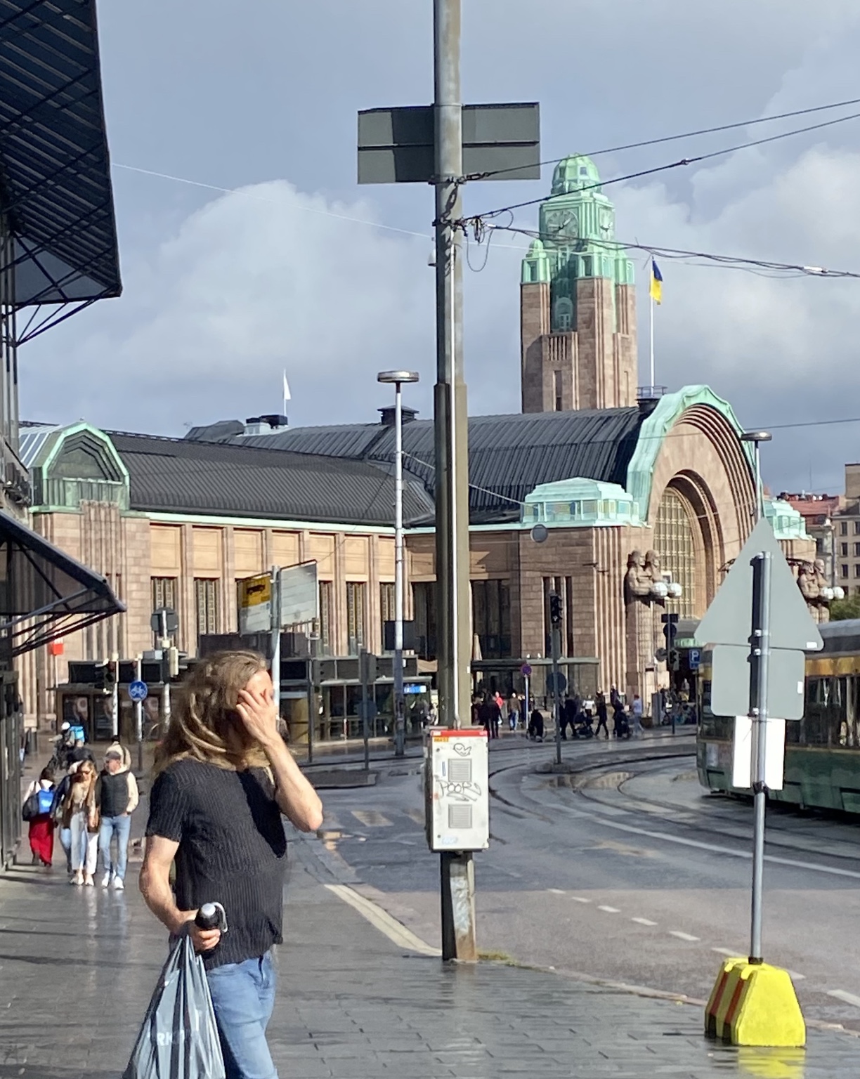 Helsinki Central Railway Station seen from a busy city street with a Ukrainian flag flying from its clock tower