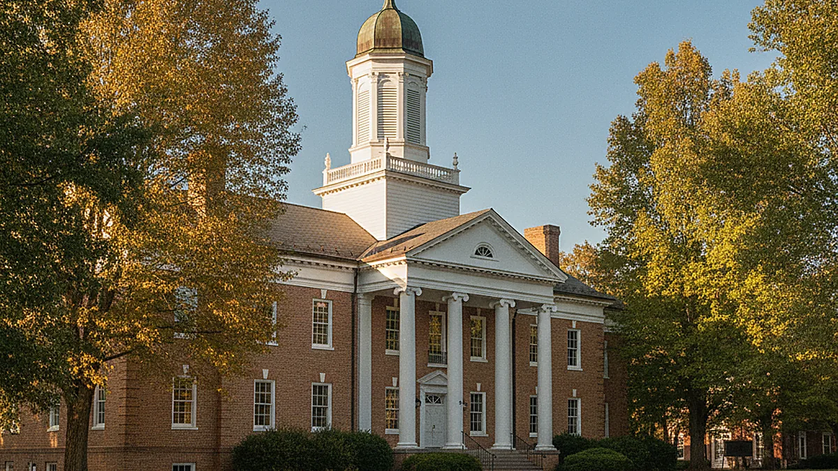 Historic red-brick college building with white columns and a domed cupola framed by autumn trees in a North Georgia town