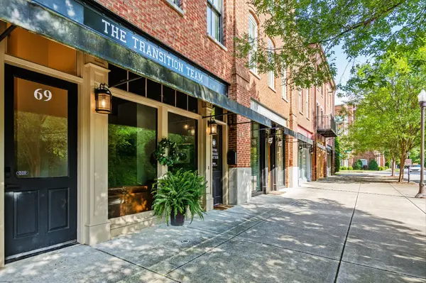 Frustrated with underperforming property management? Discover Huntsville and Madison's #1 trusted partner for landlords and investors. Exterior of The Transition Team office at 69, brick building along tree-lined sidewalk in a town center 