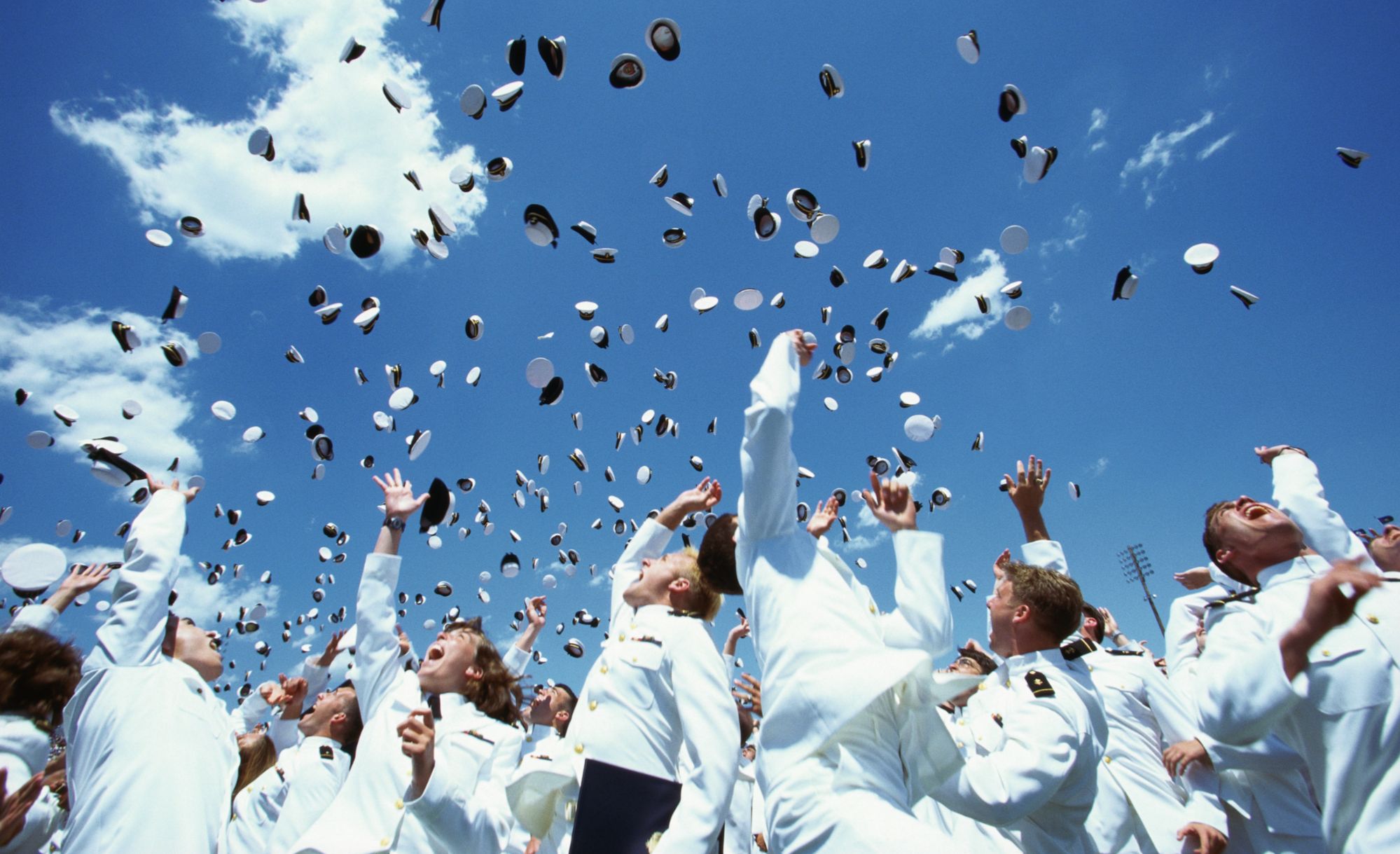 U.S. Naval Academy graduates in white uniforms tossing their covers during Commissioning Week in Annapolis