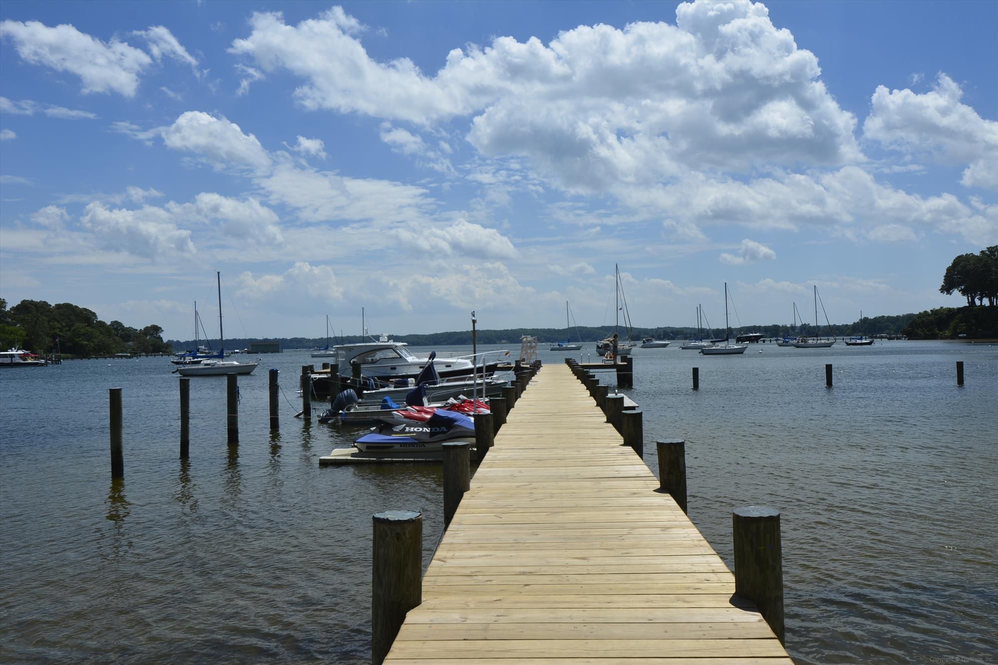 A long wooden community pier with boats tied alongside, reaching into Sullivan's Cove