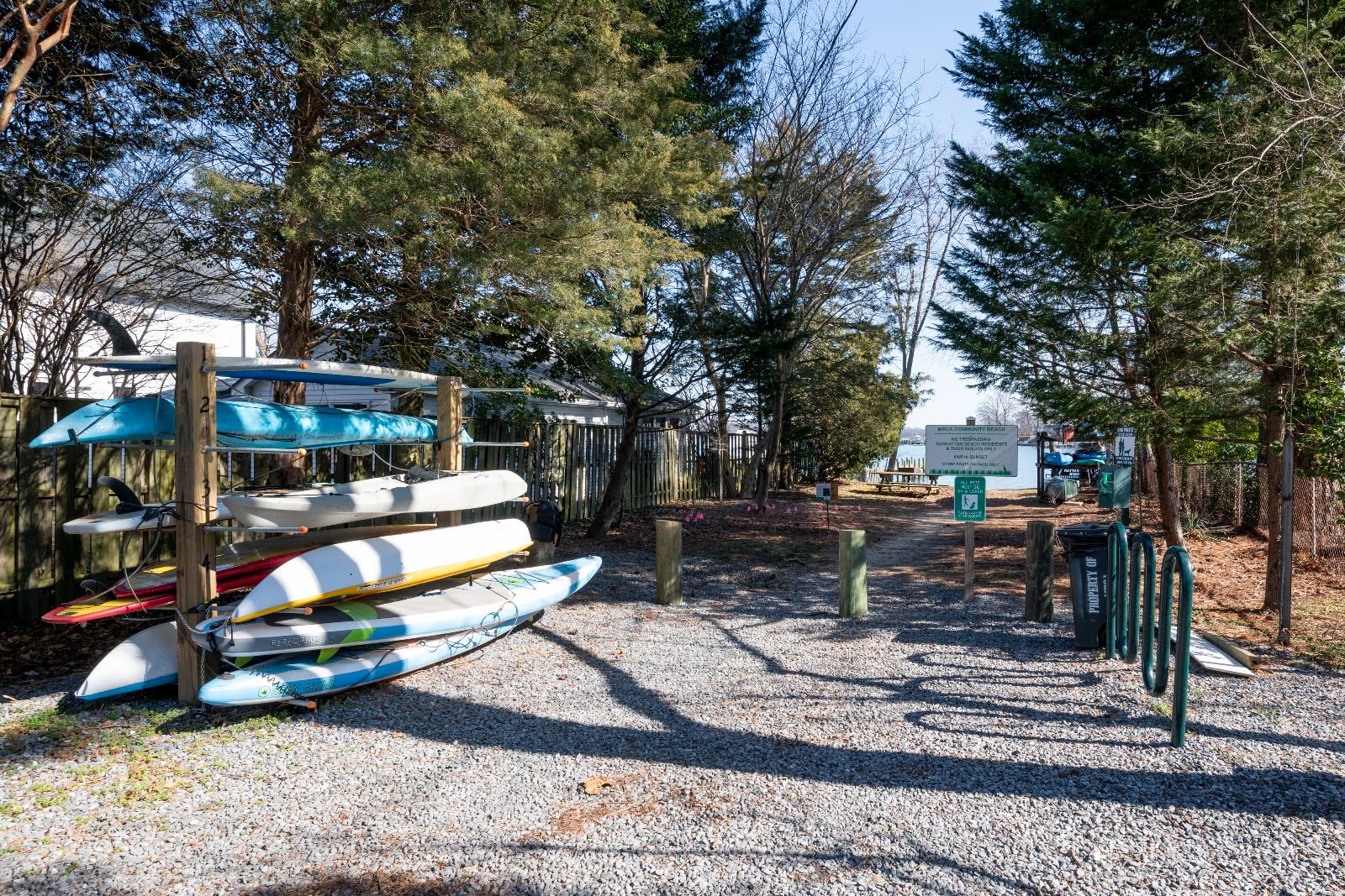 Wooden paddlecraft racks holding kayaks and paddleboards near a community beach