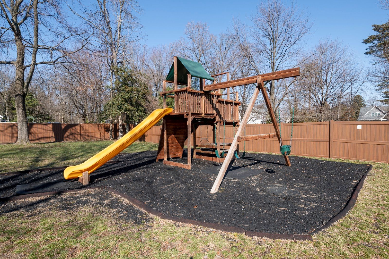 Wooden playset with a yellow slide beside the Manhattan Beach clubhouse