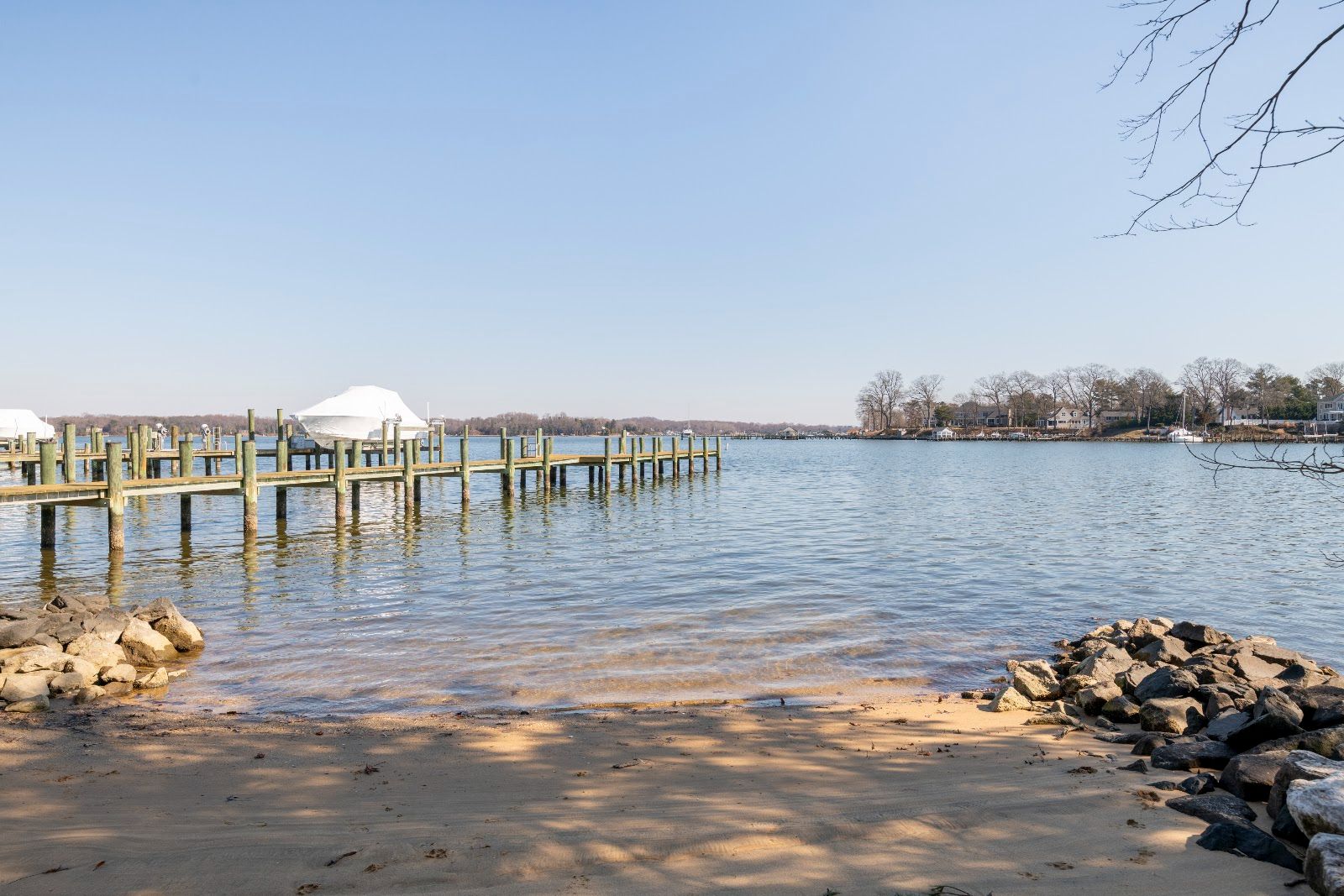 A sandy community beach at the water's edge, with rocks on either side and piers across the creek