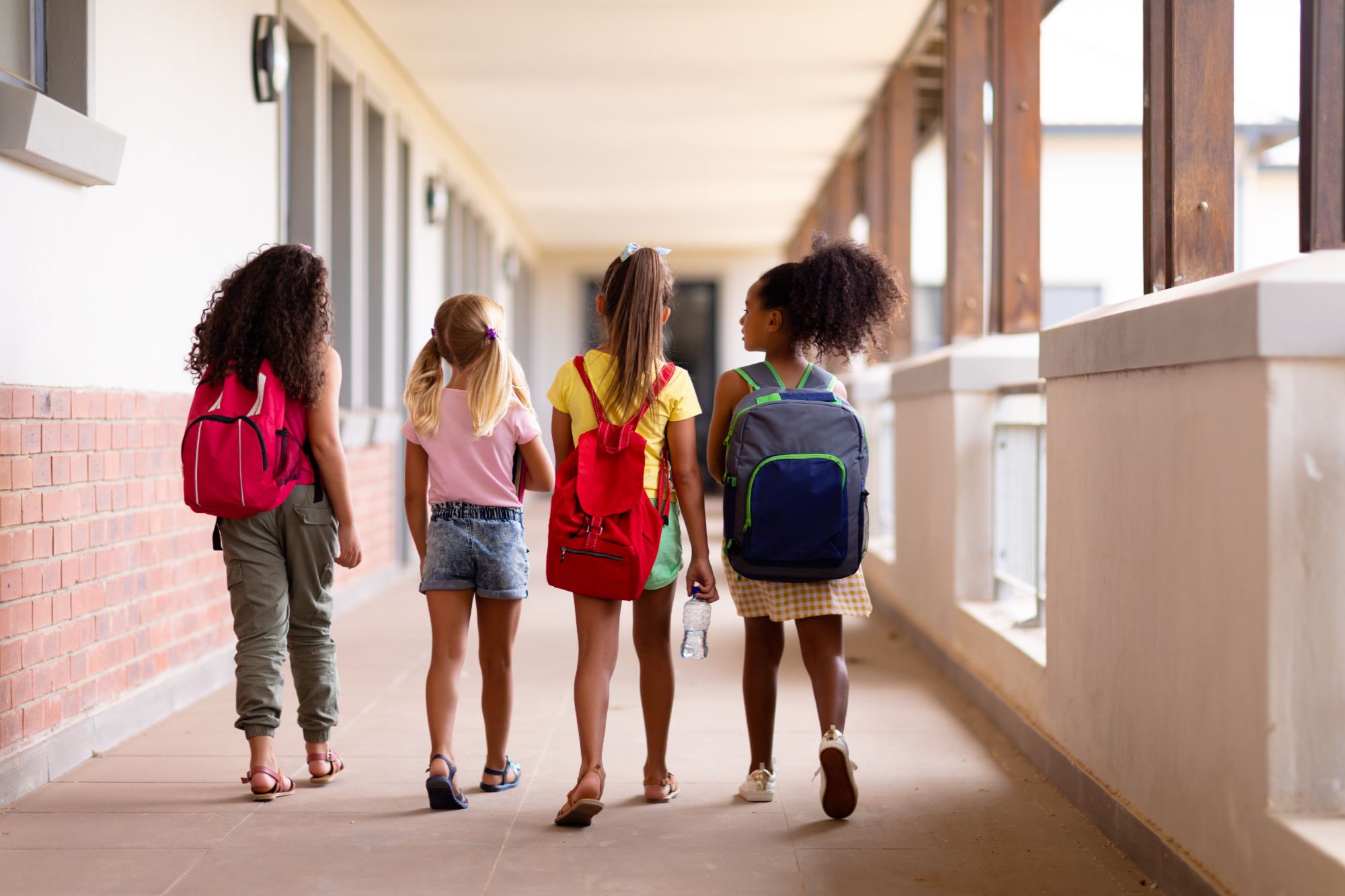 Students walking down a school hallway with backpacks