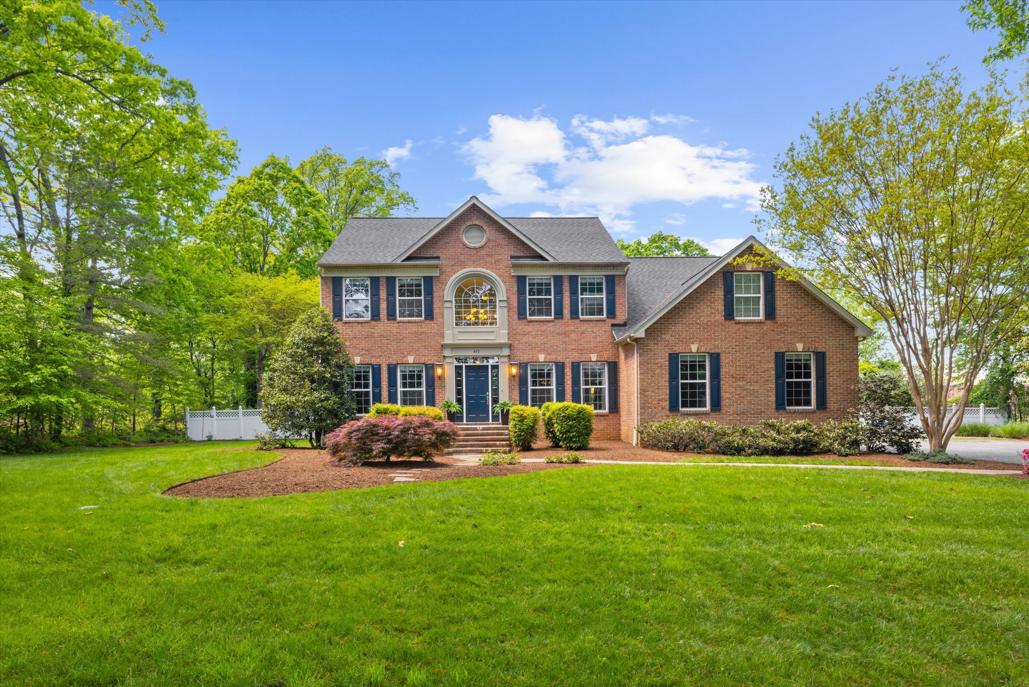 Front exterior of a classic two-story single-family residential home with a green lawn and mature trees in Anne Arundel County, Maryland.