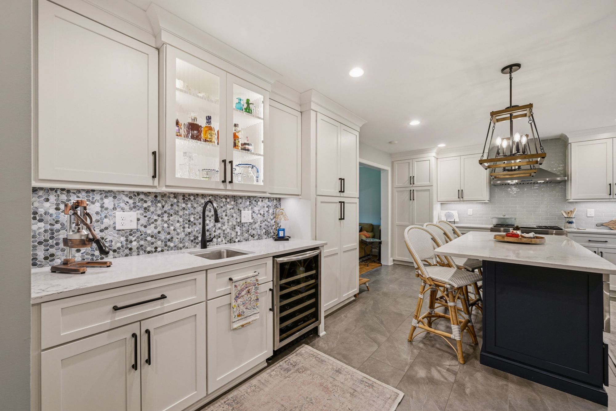 Modern staged home kitchen in Anne Arundel County, Maryland, featuring white cabinets, a tiled backsplash, and a kitchen island with seating.