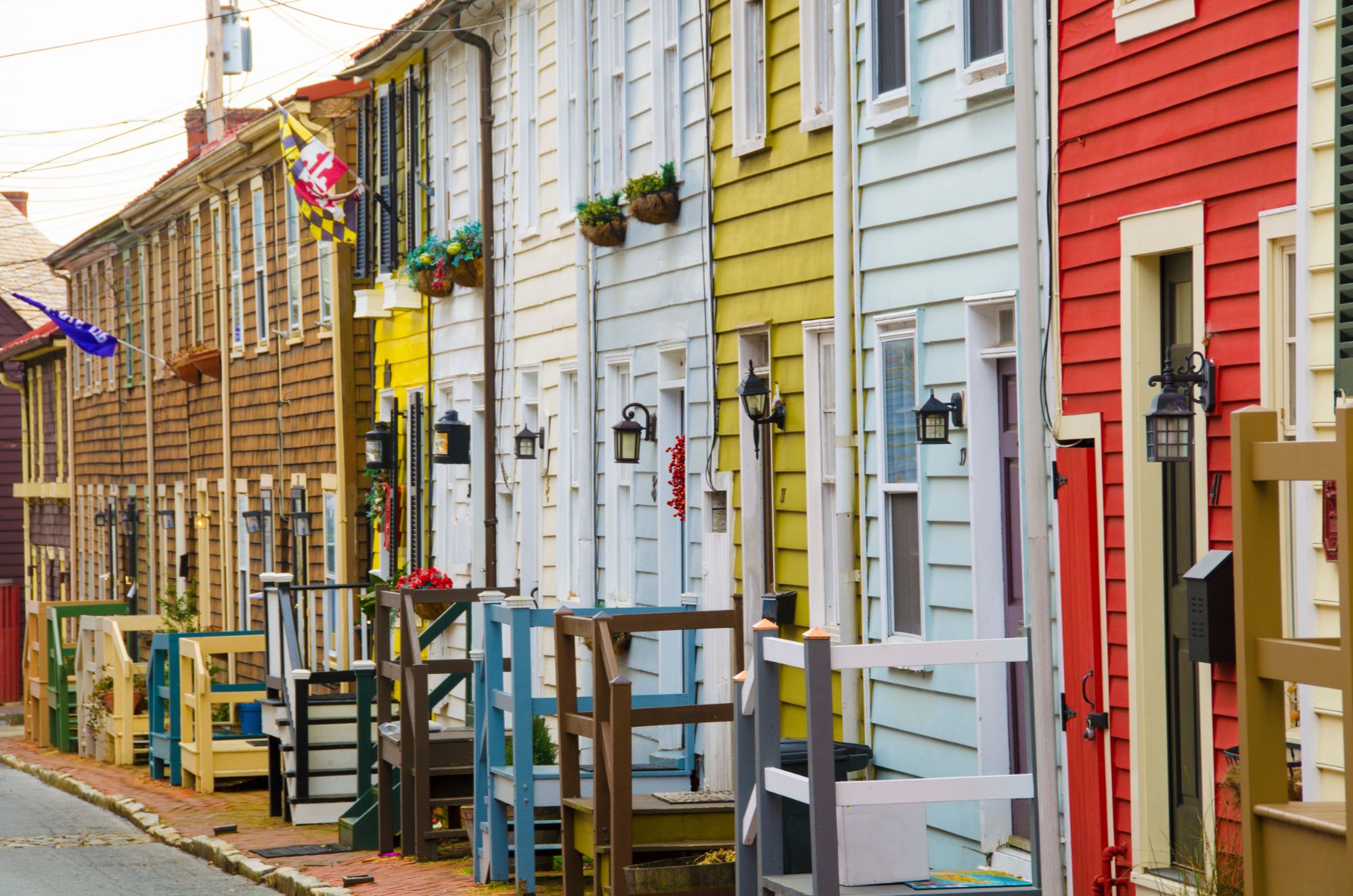 Row of historic, colorful row houses with painted brick facades along a street in downtown Annapolis, Maryland.
