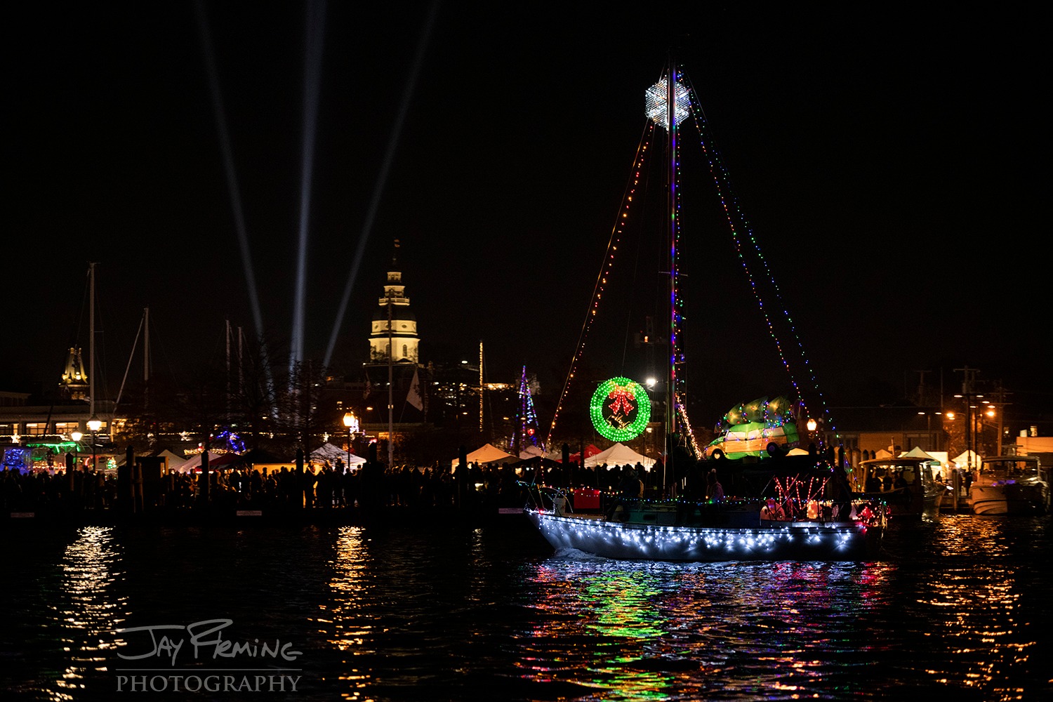 A sailboat covered in holiday lights passes the Maryland State House during the Eastport Yacht Club Lights Parade