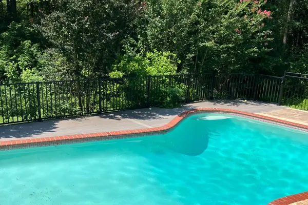 Curved in-ground pool with brick coping backing to a private wooded tree line at 148 Waldo Rd, Pasadena MD