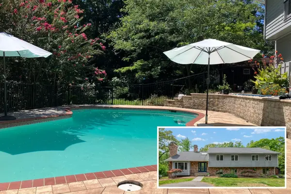 In-ground pool with brick patio, umbrellas, and stone retaining wall in the fenced backyard at 148 Waldo Rd, Pasadena MD