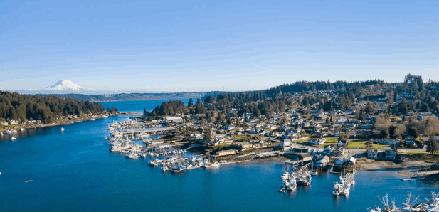 Aerial view of Gig Harbor, Washington with boats docked in the marina, downtown buildings, and Mount Rainier in the distance