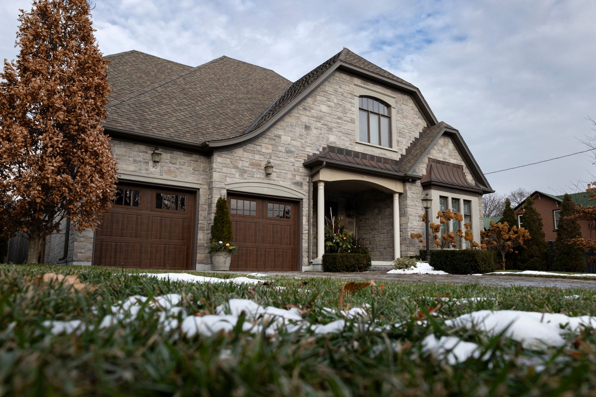Stone-and-stucco custom detached home with a double garage and winter lawn in an Oakville-style GTA neighbourhood