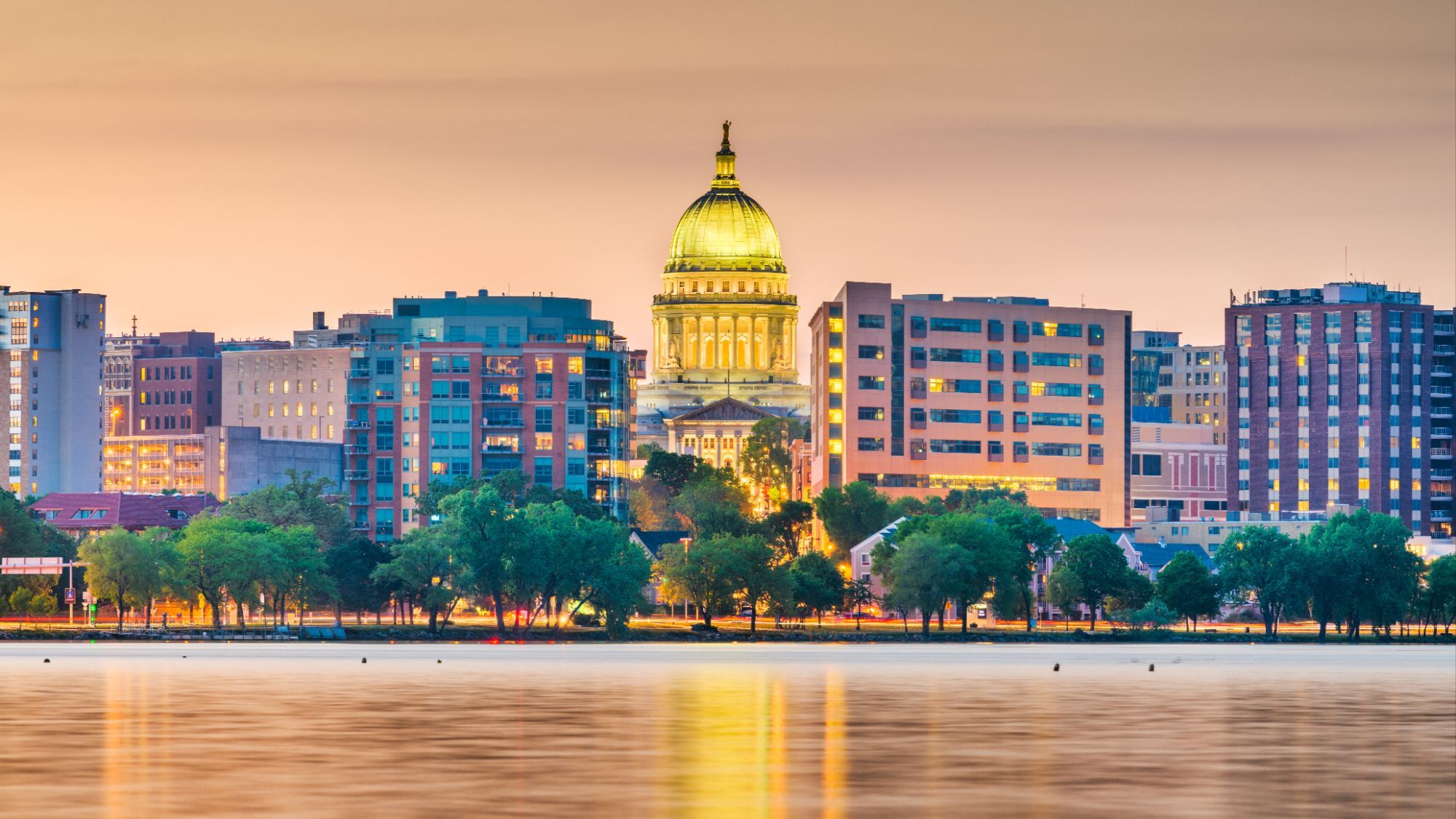 Madison, Wisconsin skyline with the State Capitol dome at golden hour, viewed across Lake Monona.