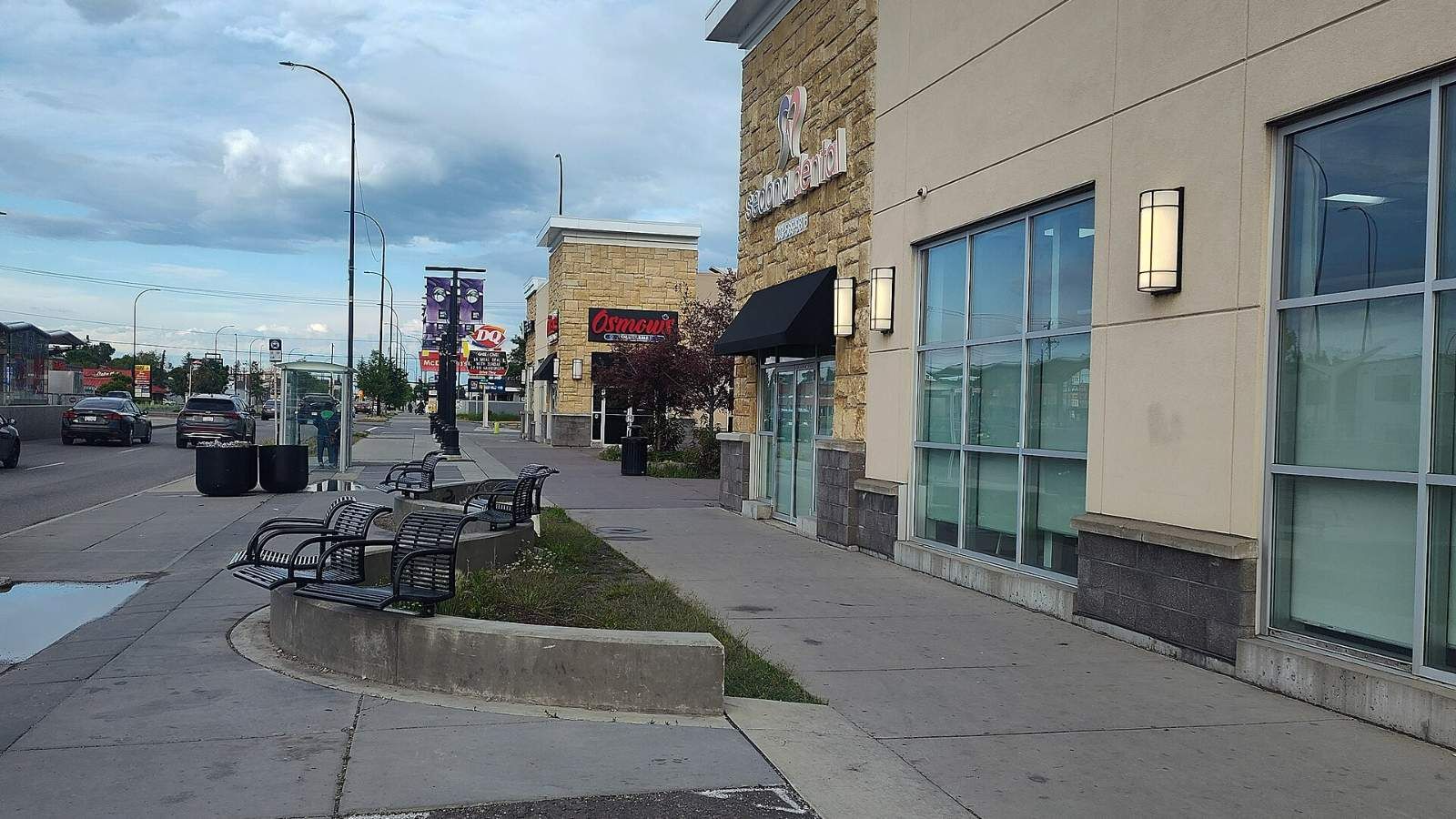 Shops, benches and a bus stop along International Avenue (17 Avenue SE) near 44 Street SE in Forest Lawn, Calgary.