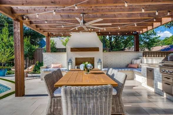 Outdoor dining table set for dinner with warm ambient lighting and greenery