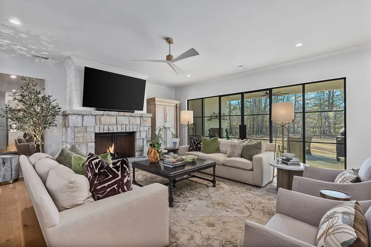 family room with a stone fireplace, a flat screen tv above and steel and glass doors to a covered patio