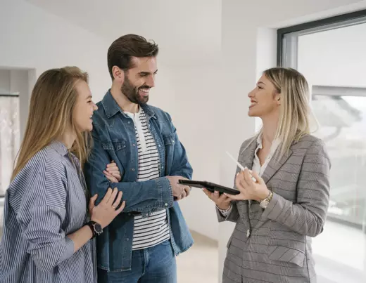 Real estate agent showing home details to smiling couple during property tour