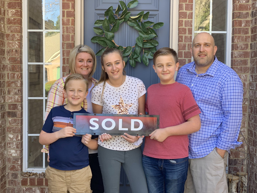 Family holding a Sold sign