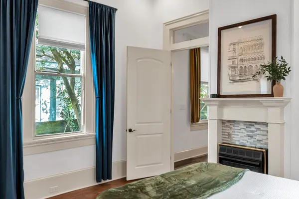 Staged bedroom with blue velvet drapes and framed sketch over the mantel