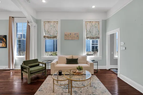 Staged sitting room with green velvet chair and gold nesting tables