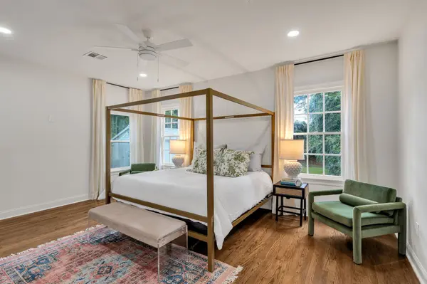 Staged primary bedroom with gold canopy bed and green velvet chair