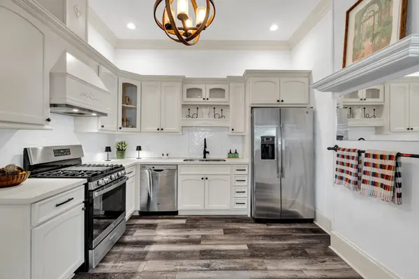 Staged kitchen with white cabinetry and globe pendant light