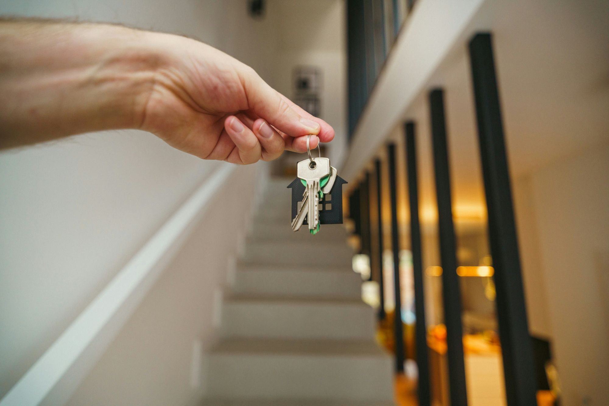 A homeowner or landlord holding keys in front of their property