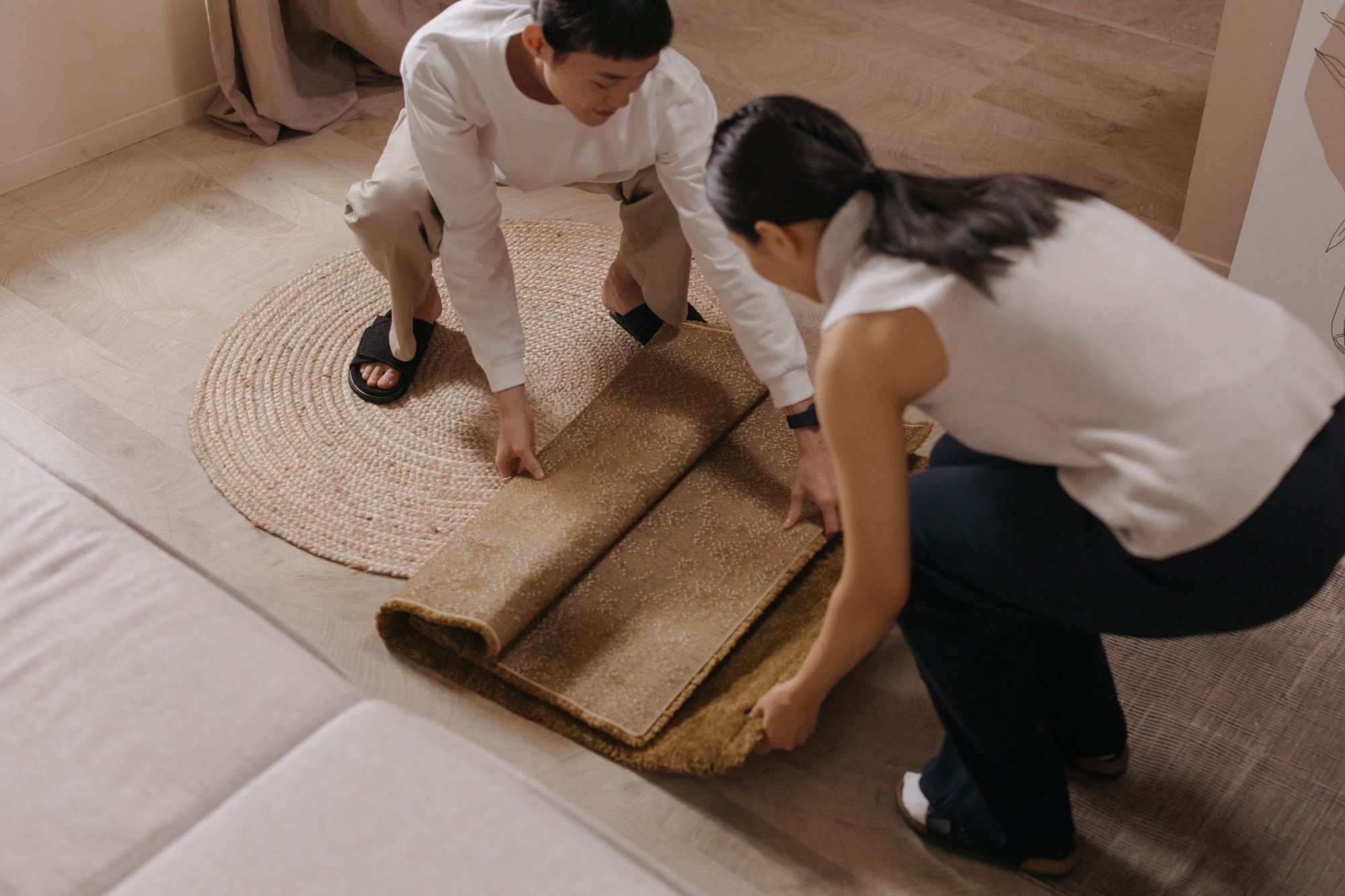 A couple rolls out a rug in a room
