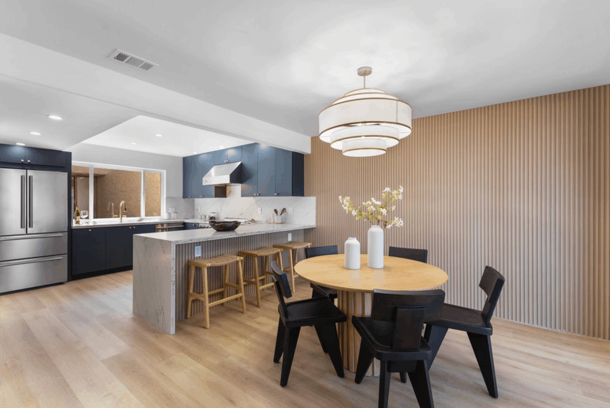 Remodeled kitchen with navy cabinets opening to a dining area