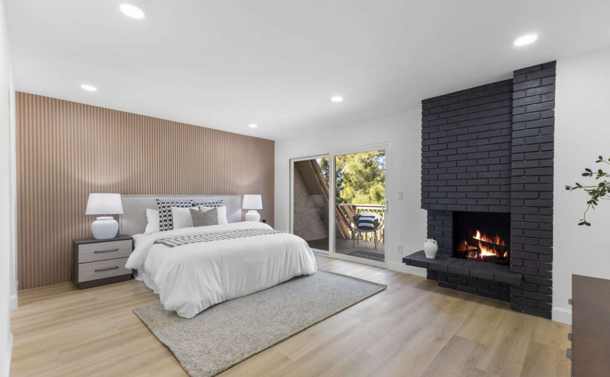 Primary bedroom with a corner brick fireplace and a sliding door to a balcony