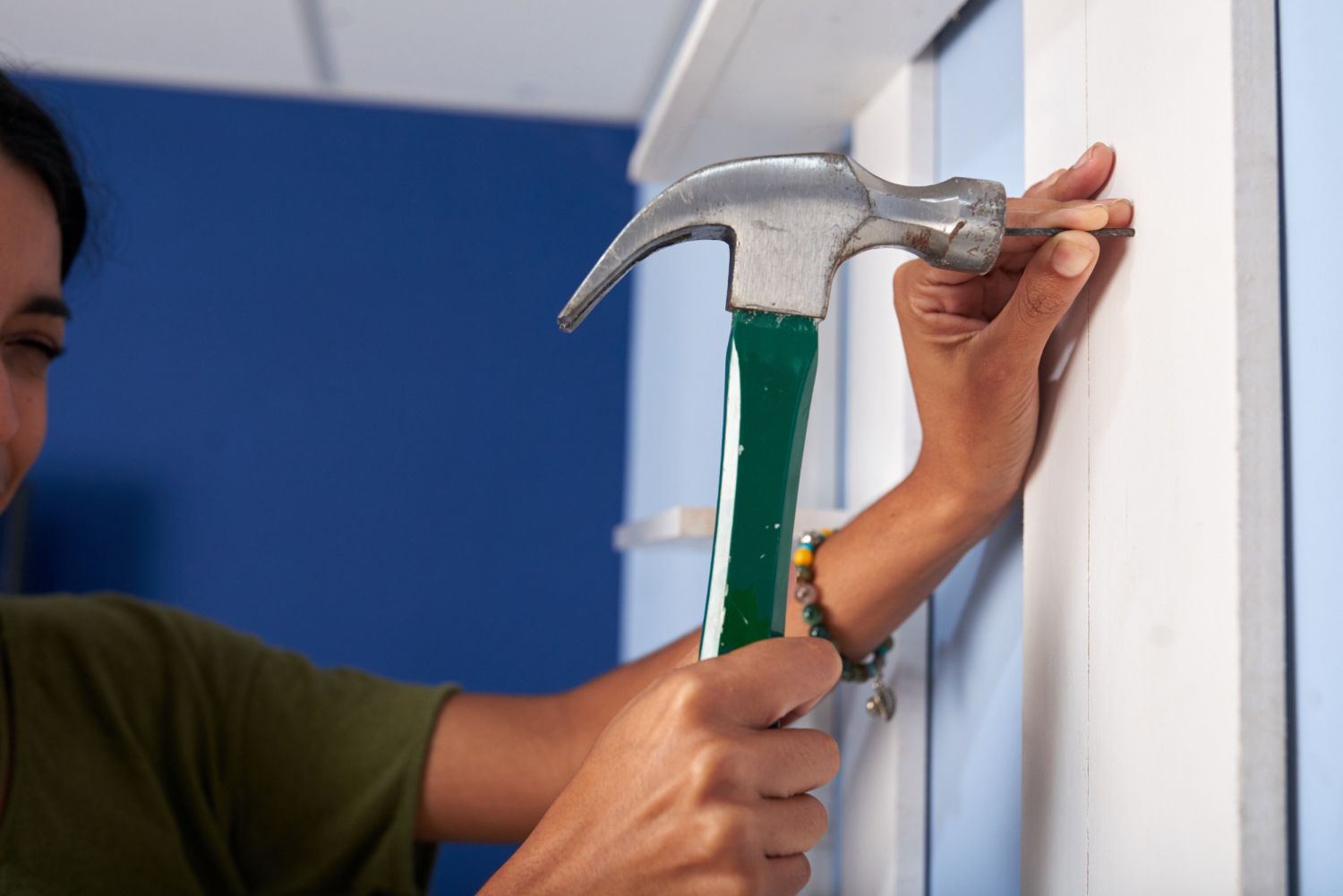 woman hammering nail into wall to repair it