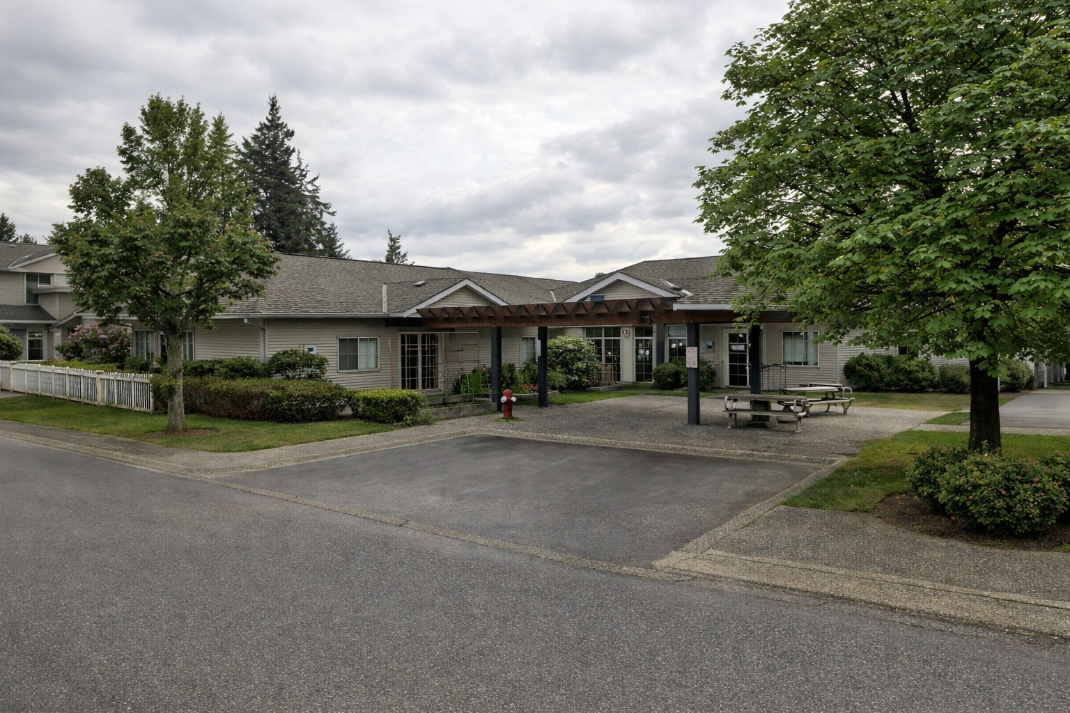 Street-level view of the amenities building at Maple Court in Surrey BC, featuring covered entrance, landscaped grounds, and outdoor seating area
