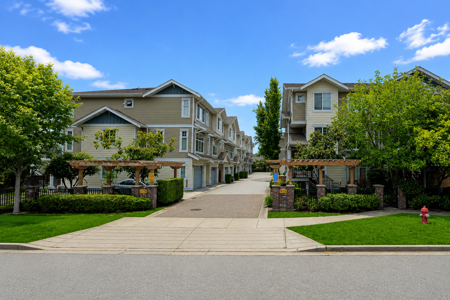 Street-level entrance view of Lotus Townhomes at 16355 82 Avenue in Surrey BC, featuring landscaped grounds, townhouse buildings, visitor entrance, and a well-maintained Fleetwood residential community on a sunny day.