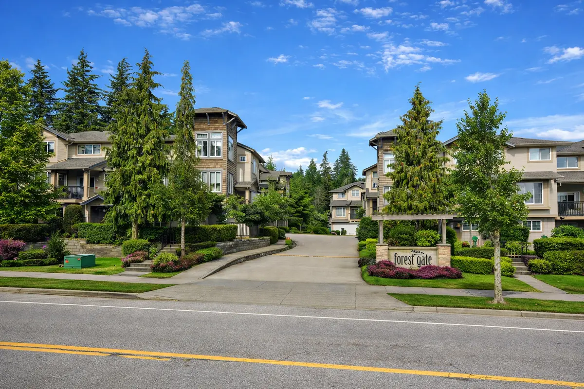 Street view of Forest Gate townhomes at 5839 Panorama Drive in Surrey BC with blue sky, lush green landscaping, and entrance signage visible from the road