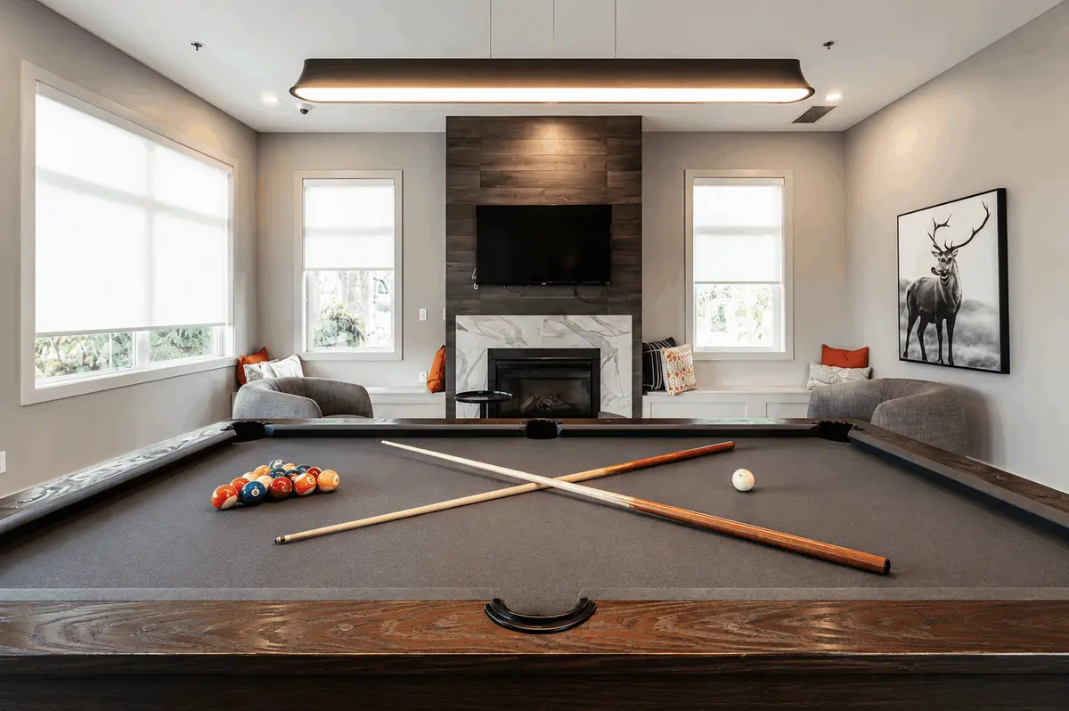 Modern clubhouse games room at Canopy at Tynehead Park in Fleetwood, Surrey, featuring a full-size pool table, contemporary fireplace lounge, comfortable seating, large windows, and stylish community amenity space for residents.