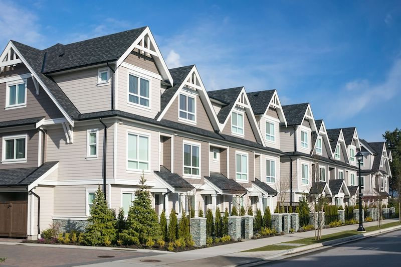 Side-by-side comparison of a Langley townhouse and a detached Surrey home under blue skies