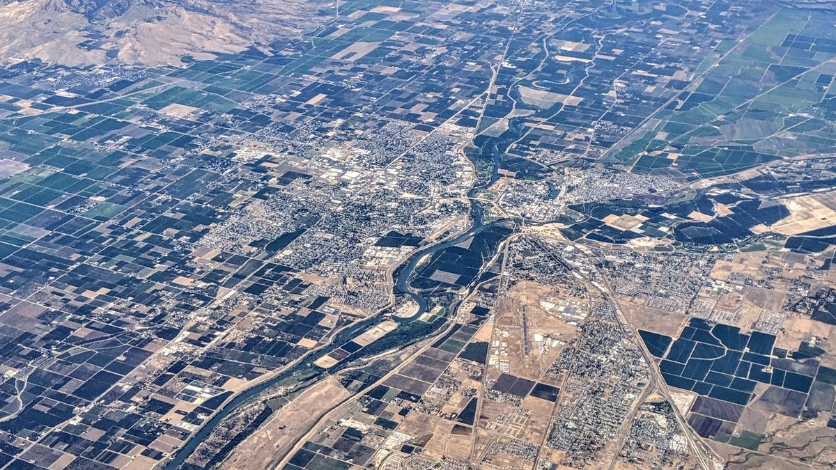 Aerial view of Yuba City and Marysville on either side of the Feather River, surrounded by a patchwork of orchards and farmland, with the Sutter Buttes at the upper left