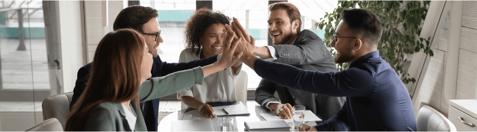 Diverse professionals high-fiving at office meeting about real estate concierge savings program.