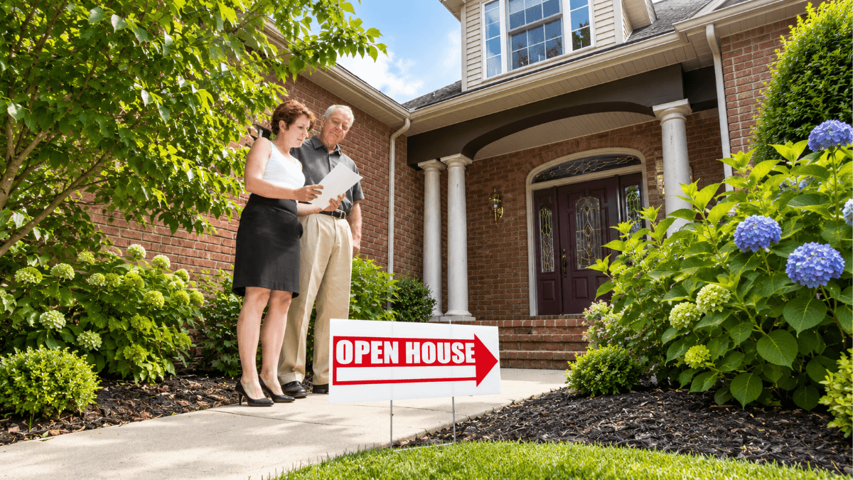 Open house sign outside a Dallas home with prospective buyers reviewing property information