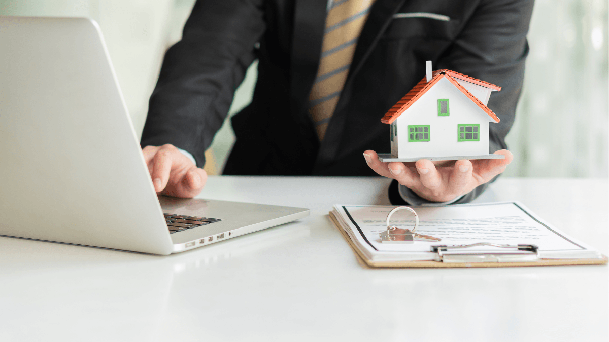 Real estate professional reviewing a home offer with a model house, contract and laptop, illustrating why the first offer on a Dallas-area home should be evaluated on price, terms, financing and overall strength rather than assumed to be only a starting point
