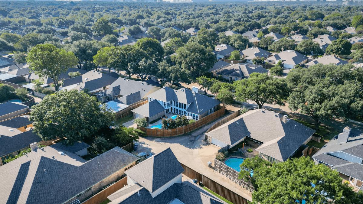Aerial view of an established North Dallas neighborhood with mature trees, large homes and backyard pools, illustrating the space, character and lifestyle buyers may find around the $800K price point