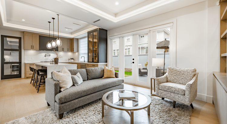 Bright modern living room with open-concept kitchen in a newly built home in San Diego County, featuring large windows and contemporary finishes.
