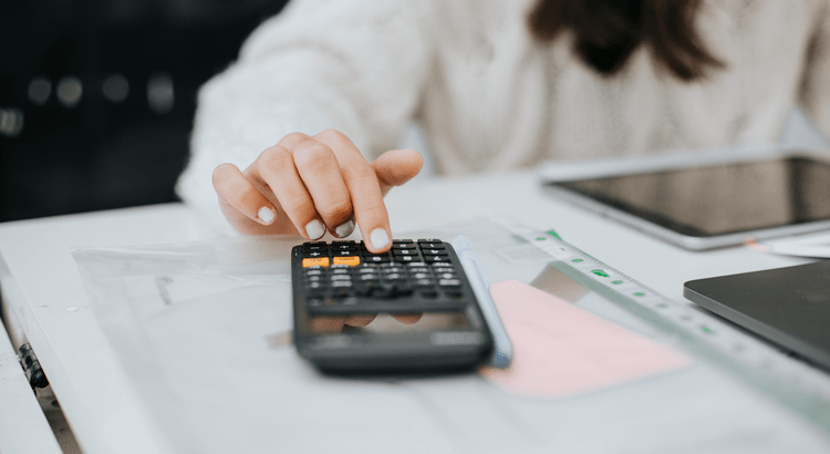Homebuyer using a calculator to plan housing budget and affordability in North San Diego County.