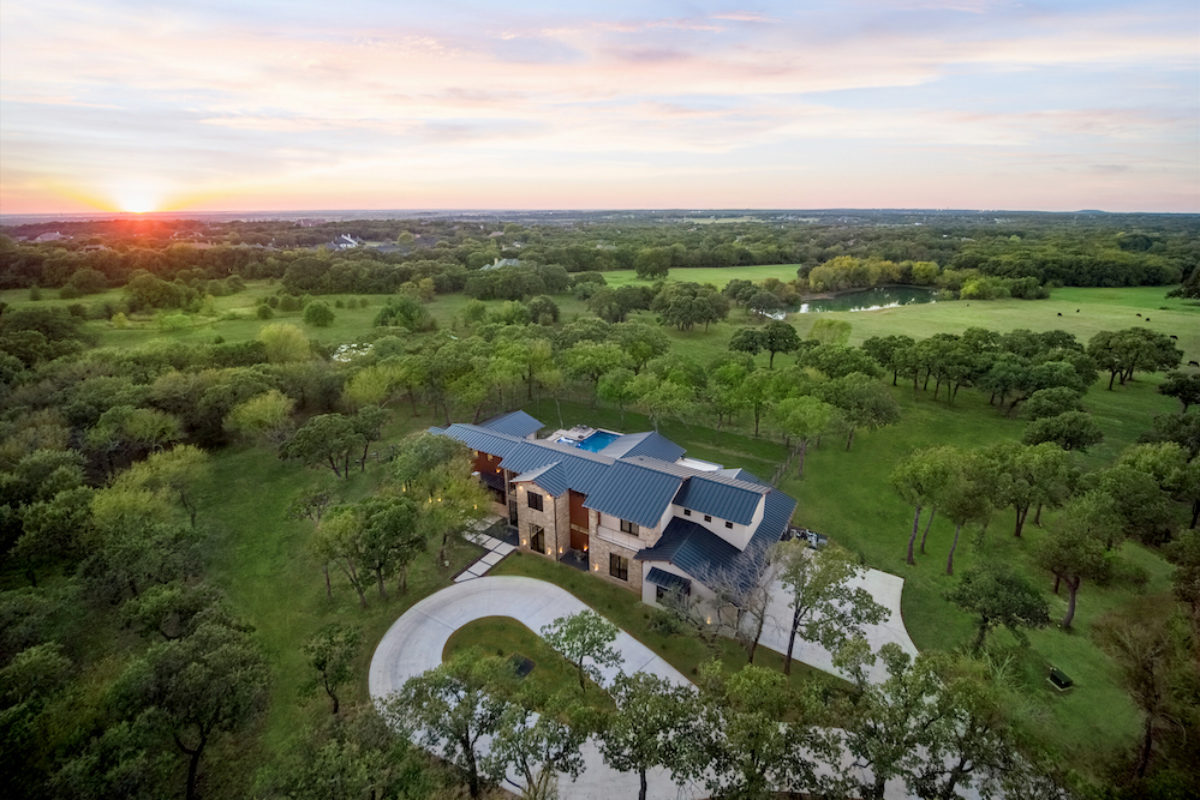 Aerial view of a luxury ranch estate in North Dallas with gated entry, barns, and pastureland