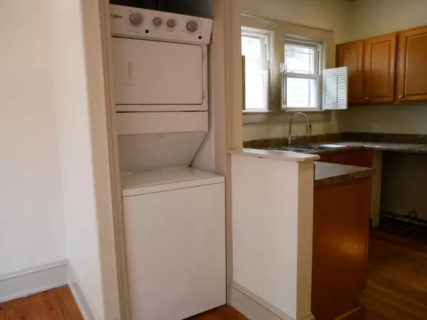 Interior room with hardwood floors, ceiling fan, and recessed lighting leading into kitchen with wooden cabinets.