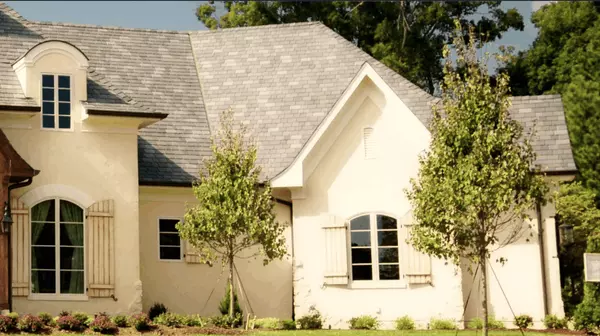 Elegant Texas luxury home with custom wood accents, dormer windows, and lush front landscaping — a prime example of upscale real estate ideal for sellers in premium markets.