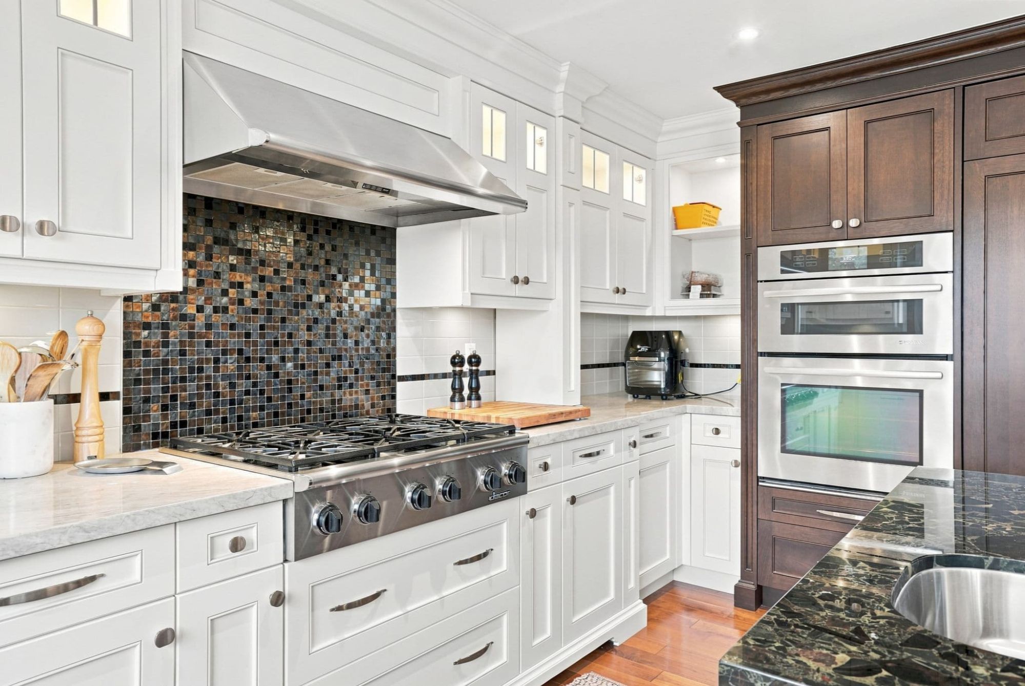 Luxury kitchen with dark wood cabinetry, expansive stone island, pendant lighting and open-concept living area